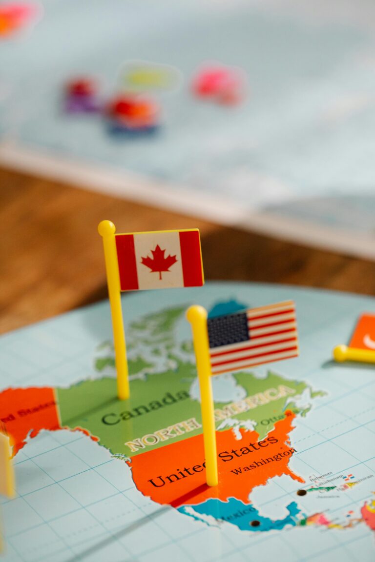 Beasiswa USA - Canada Close-up of miniature Canada and USA flags on a world map depicting North America, symbolizing travel and education.